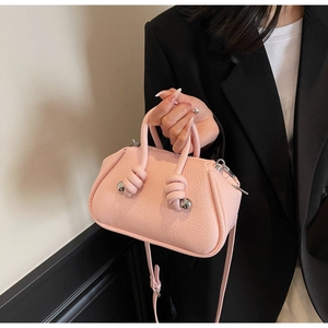 Dettaglio borsa in pelle rosa con manico annodato e decorazione a sfera in metallo argento