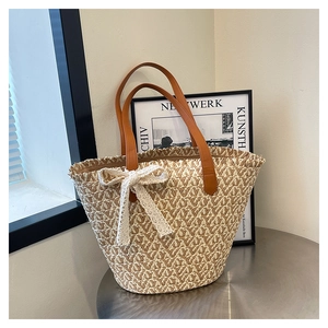 Detail of straw tote bag featuring white lace bow and brown leather shoulder straps