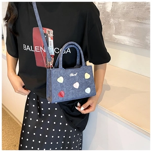 Détail du sac carré en denim bleu avec cinq patchs de cœur colorés et bandoulière