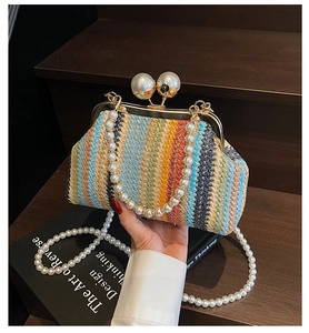 Detail of colorful woven straw evening clutch with large pearl clasp and pearl strap