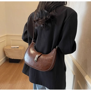 Model wearing a dark brown crescent hobo bag with silver metal buckle on the shoulder