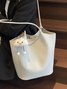 Chic beige lychee pattern bucket bag with cloud pendant on stylish black blazer outfit