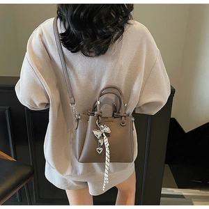 Detail of lychee pattern brown leather bucket bag with silver butterfly charm