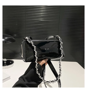 Detail of glossy black patent leather baguette bag with silver chain strap and zipper