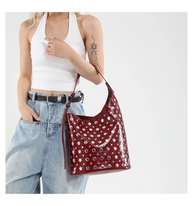 Détail du sac seau bordeaux style punk avec clous argentés et finition en cuir brillant