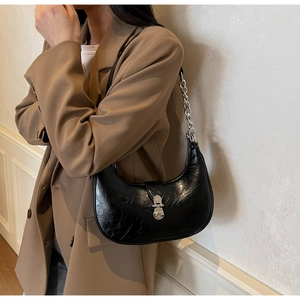 Detailed close-up of a black PU leather crescent bag with a silver chain and metal clasp