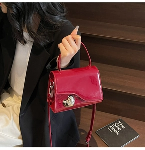Dettaglio della mini borsa in vernice rossa con fibbia a cuore argento e manico