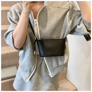 Borsa a secchiello nera in pelle a grana litchi indossata con un completo sportivo chic