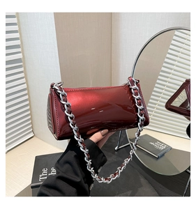 Close-up of glossy burgundy patent leather bag with a chunky silver metal chain strap