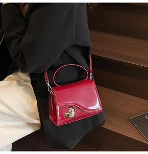 Dettaglio della borsa in pelle verniciata rossa con fibbia a cuore in metallo argentato