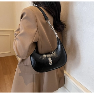 Detail of a black crescent hobo bag with silver chain strap on a chic blazer