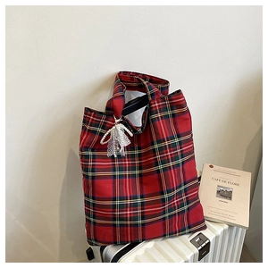 Detail of red plaid tote bag with elegant white lace and pearl bow charm accessory