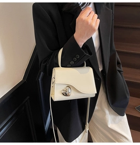 Dettaglio mini borsa in pelle verniciata crema con chiusura a cuore argento e tracolla