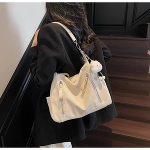 Vue détaillée du sac cabas blanc en cuir minimaliste avec fermeture éclair et breloque
