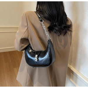 Detailed view of black crescent hobo bag with silver chain strap and shiny faux leather