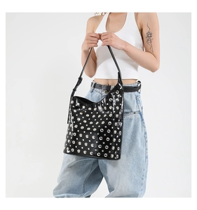 Détail d'un sac à bandoulière punk noir avec clous argentés et finition brillante