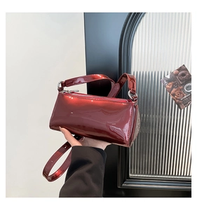 Close-up of a burgundy patent leather crossbody bag with silver zipper and sleek texture