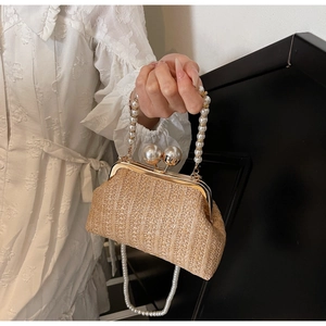 Detail of hand-woven straw evening bag with elegant pearl handles and metallic clasp