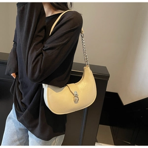 Detail of light beige crescent shoulder bag featuring silver chain and metal push lock