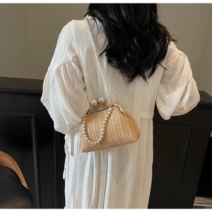 Detail of straw woven evening bag with large pearl clasp and long pearl strap