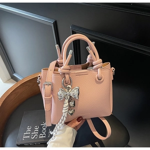Close-up of pink lychee leather bucket bag with silver metal bow and heart pendant charm