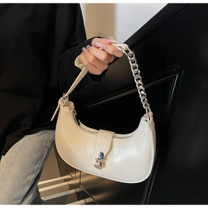 Detail of a creamy white half-moon bag featuring a shiny PU finish and silver metal buckle