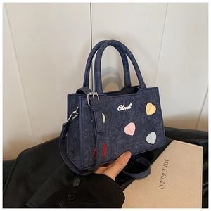 Vue détaillée du sac à main en denim bleu foncé avec patchs de cœur et bandoulière