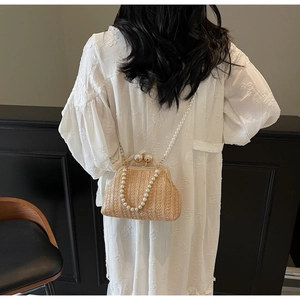 Detail of straw woven bag featuring elegant pearl straps and golden ball clasp closure
