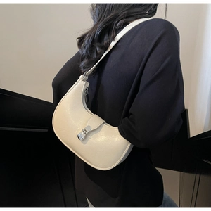 Detail view of cream white half-moon shoulder bag with silver metallic buckle on dark outfit