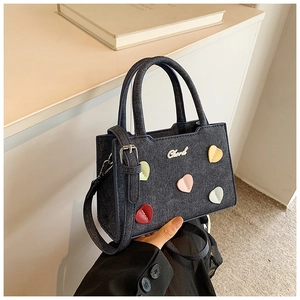 Détail du sac bandoulière en denim avec patchs cœurs colorés et sangle ajustable