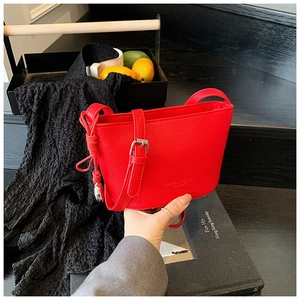 Dettaglio borsa a secchiello rossa con texture a grana litchi e fibbie in metallo argento