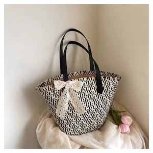 Detail of woven tote bag featuring black and white texture with a white lace bow accent