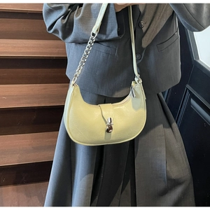 Detail of light yellow crescent shoulder bag featuring glossy pleated leather and chain strap