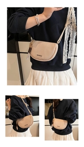 Detail of beige half-moon crossbody bag featuring woven texture and branded logo patch
