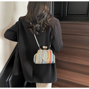 Detail of colorful striped woven clutch with large pearl clasp and shoulder chain