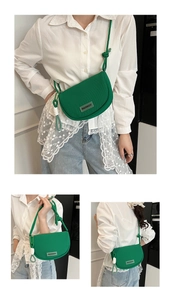 Detailed close-up of a green semi-circular crossbody bag with textured fabric and fringe