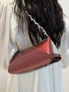 Burgundy metallic chain baguette bag shown on a model wearing a white dress for a chic look