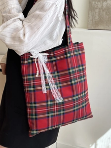 Vintage red plaid tote bag with lace bow and pearl charms worn by a model in a bright room