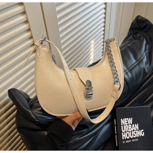 Detailed macro view of cream hobo bag with pebble leather texture and silver chain