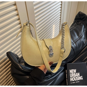 Close-up of cream yellow crescent bag featuring silver metal buckle and chain detail