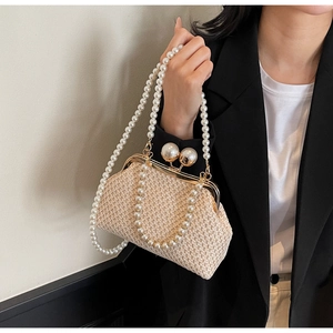 Detailed macro view of woven evening bag featuring pearl handle and decorative pearl clasp