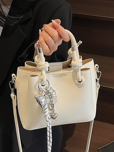 Chic beige lychee textured bucket bag with trendy knot handles and heart charm details