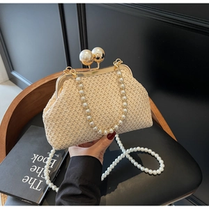Detail of a beige woven evening bag featuring gold metal frames and large pearl clasps