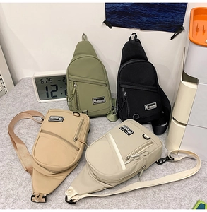 Détail de quatre sacs bandoulière en nylon vert, noir, kaki et gris avec poches zippées