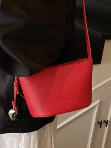 Elegante borsa a secchiello in pelle rossa con ciondolo a cuore sulla modella