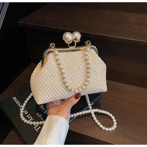 Detail of straw evening bag featuring gold clasp and elegant double pearl handle strap
