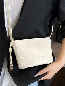 Borsa a secchiello bianca con grana litchi, ciondolo a cuore e tracolla annodata