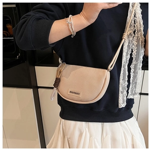Detail of minimalist beige saddle crossbody bag with woven texture and lace ribbon strap