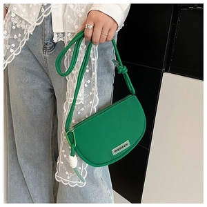 Detail of green crescent crossbody bag with woven texture and knotted shoulder strap