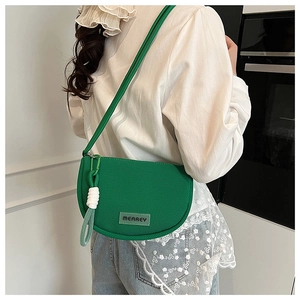 Detailed close-up of green knitted saddle bag featuring fabric texture and white rope knot